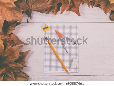 Empty white paper and school supplies on wooden table with autumn leaves.Back to school
 Image is intentionally toned.