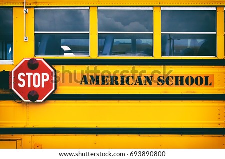 Classic yellow american school bus transporting children to the school. Back to school concept. Red stop sign on school bus side.