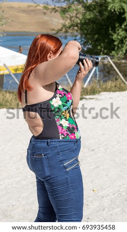Thick woman photographer on the beach