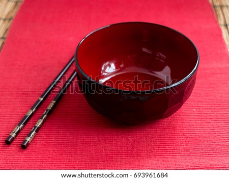 Empty Red Rice Bowl with Chopstick on red background,  shallow depth of field