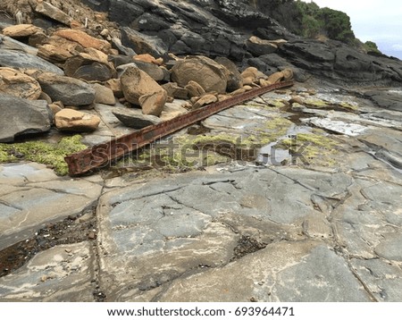 Rusty steel beam on the rocky coast