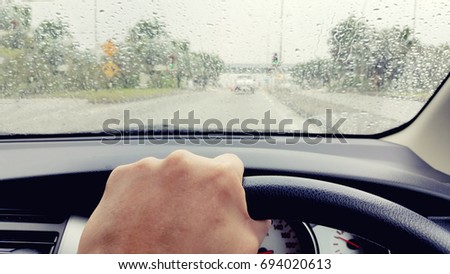 driving during rainy day, view from car window, blurry raindrops on window.