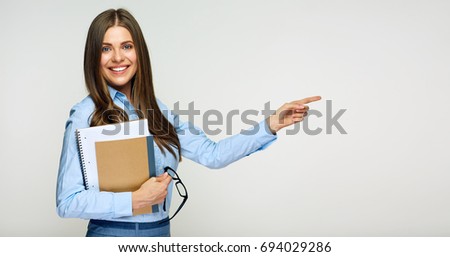 Smiling teacher woman holding book pointing finger at copy space.