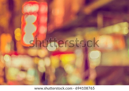 Abstract blur image of food stall at night market on street for background usage . (vintage tone)