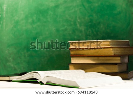 Textbooks and books on a dark wooden table. Beautiful green background.
