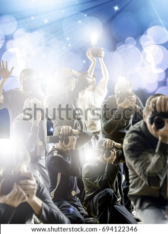 Crowd of paparazzi with flashing cameras in front a flash bright blue background.