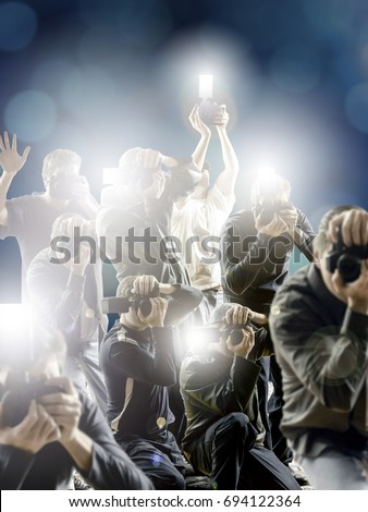 Crowd of paparazzi with flashing cameras in front a dark blue background.