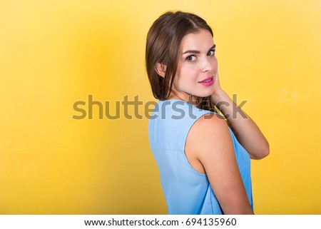 Pretty young woman standing against bright background