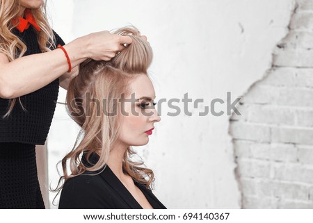 Beauty blond woman in hairdresser salon making an evening or wedding hair style Royalty-Free Stock Photo #694140367