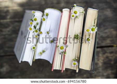 A stack of books with flowers between pages on a wooden rural table Royalty-Free Stock Photo #694156780