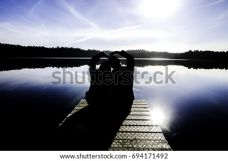 Silhouette picture of the couple sitting near the dark beautiful lake in South Island, New Zealand.