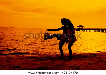 Couple is playing ball at beach during sun set