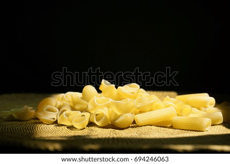 Dry noodles on thatched wicker tablecloth under morning sunlight, isolated on black background. 