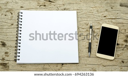 Pen, smartphone, and notebook on a wooden background.