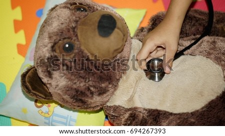 Hand holding stethoscope checking a teddy bear lungs