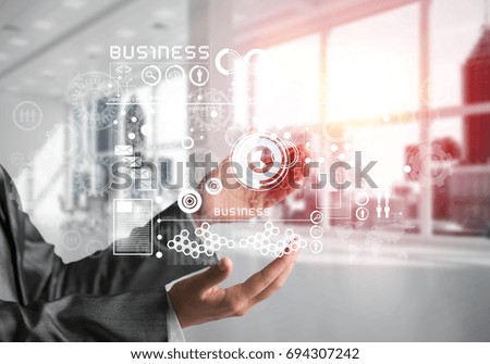 Cropped image of business woman in suit with business interface and media icons in her hands. Sunlight and office view on background. Mixed media.