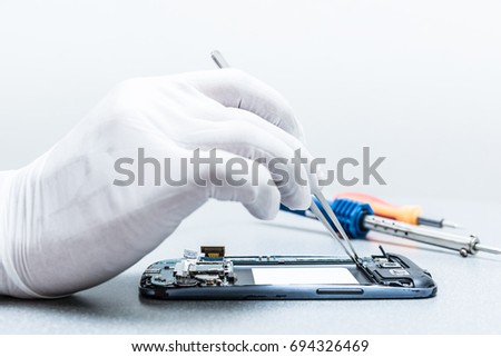 The asian technician repairing the smartphone's motherboard in the lab. the concept of computer hardware, mobile phone, electronic, repairing, upgrade and technology. Royalty-Free Stock Photo #694326469