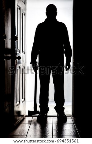 Intruder standing at doorway threshold, in silhouette with axe
