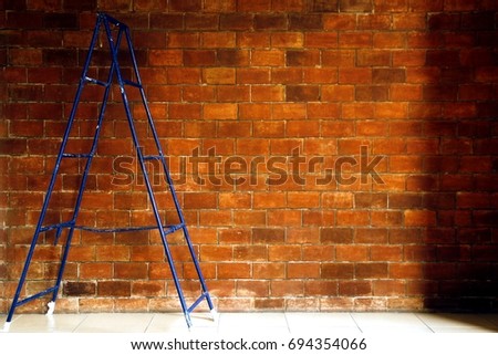 Photo of a blue steel ladder and a brick wall