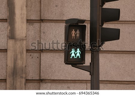 Pedestrian cross walk signal depicting two girls holding hands.