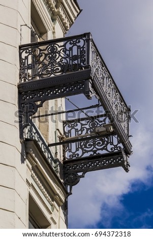 An old openwork cast-iron lattice of a balcony without a floor. Architectural detail close up.