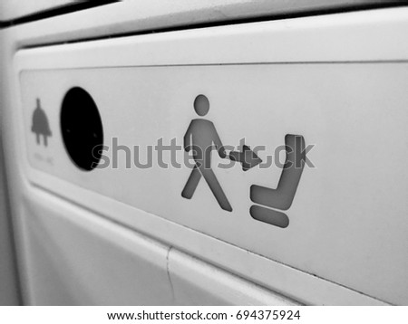 Black and white photo of Return to seat symbol in the lavatory with charging outlet on the plane the return to seat sign advice passenger to go back to the seat and fasten seat belt for safety reason