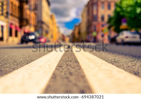 Summer in the city, the empty street. Close up view from the level of the double solid line, image in the yellow-blue toning