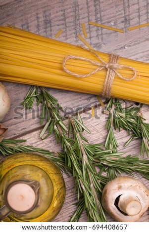 Macro picture of yellow uncooked pasta, mushroom, quail eggs and rosemary. Uncooked ingredients on a wooden table background.