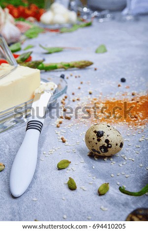 Macro picture of a glass container with butter next to a metal butter knife on a gray background. Cooking concept.