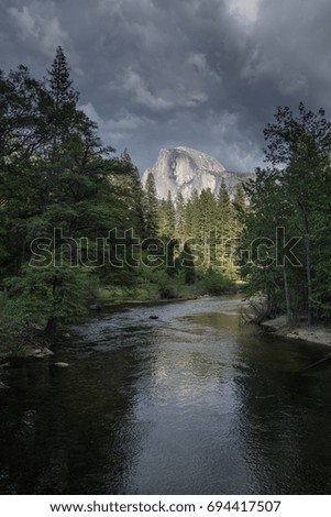 Half Dome and the Merced River, in California's Yosemite National park as a thunderstorm rolls in