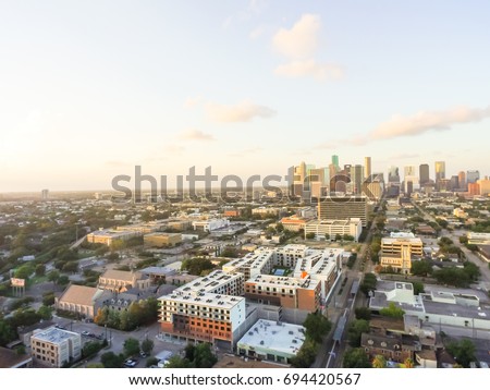 Aerial view Midtown, a business management and entertainment district southwest of Downtown Houston at sunset. Office building, restaurant, parking lot, church and high-rise, skyscrapers in background