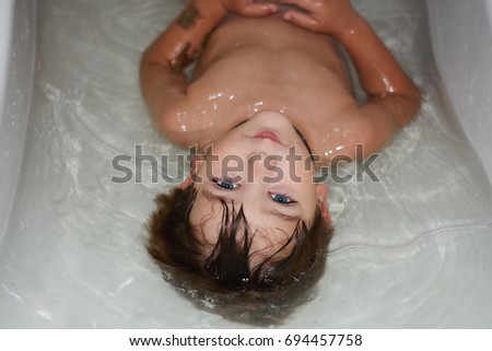 Beautiful, cute, happy, smiling, blue-eyed boy Brown takes a bath.