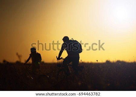 Dad and daughter travel by bicycle at sunset