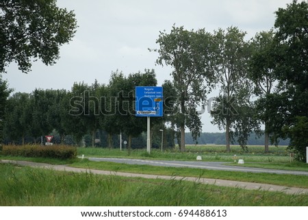 Blue board next to the road with directions in Urk.