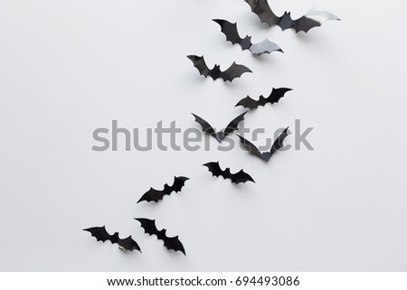 halloween, decoration and scary concept - black paper bats flying over white background