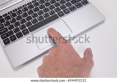 Close up of a man pressing the mouse tracking pad on a computer laptop with his finger on a white background with copy space.