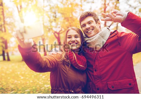 love, technology, relationship, family and people concept - smiling couple taking selfie by smartphone in autumn park