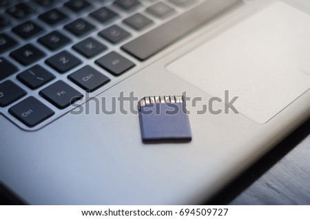 SD memory card on top of computer. 
Background for technological theme.