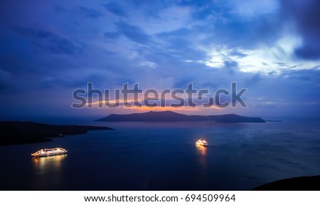 Cruise ships are resting in harbour at Santorini, Greece, after the sunset, in the blue light of the sky. Royalty-Free Stock Photo #694509964
