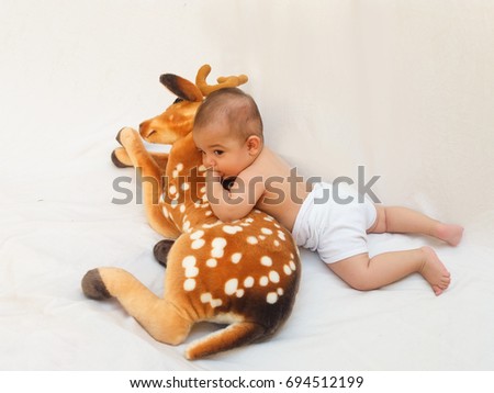 4 months old baby boy playing with soft toy dear