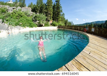 An adult female goes for a swim at Granite Creek Hot Springs, a natural hot spring in Jackson Hole, Wyoming. Fisheye view Royalty-Free Stock Photo #694516045