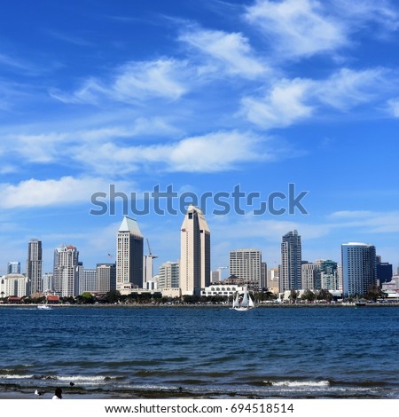 San Diego Skyline from across the water with blue sky an white trail of clouds