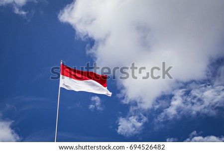 Indonesian Flag, Red and White, with blue sky background Royalty-Free Stock Photo #694526482