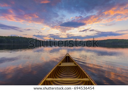 Bow of a cedar canoe on a lake at sunset - Haliburton, Ontario, Canada Royalty-Free Stock Photo #694536454