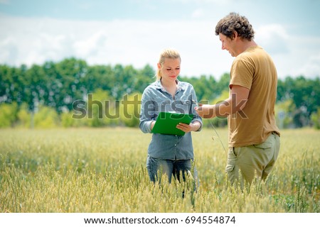 Farmer and agronomist discussing about future crop of wheat, at the field Royalty-Free Stock Photo #694554874
