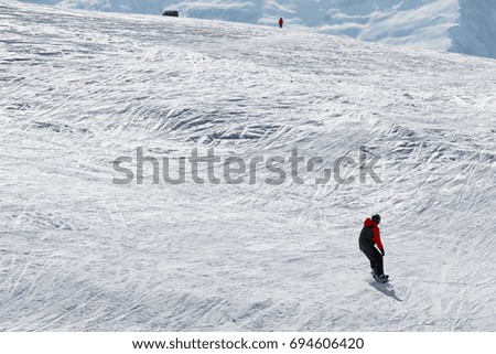Snowboarder and skier downhill on snow off-piste slope in sun winter day. Caucasus Mountains, Georgia, region Gudauri.