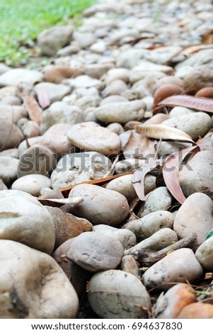 A pile of stones on the garden ground floor with blurred a green grass background 