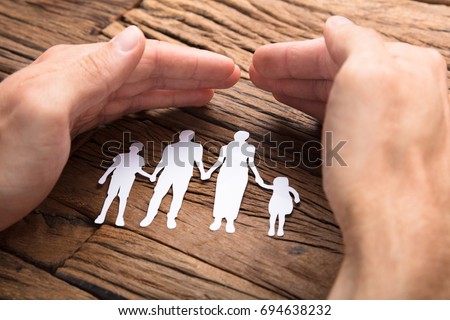 Cropped image of businessman covering paper family at wooden table Royalty-Free Stock Photo #694638232