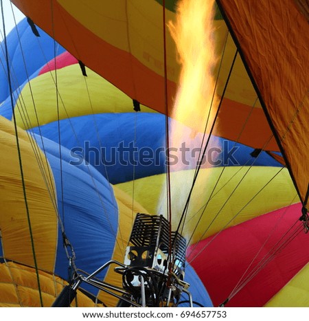 A closeup photo of flames shooting into a hot air balloon as it prepares to take off.