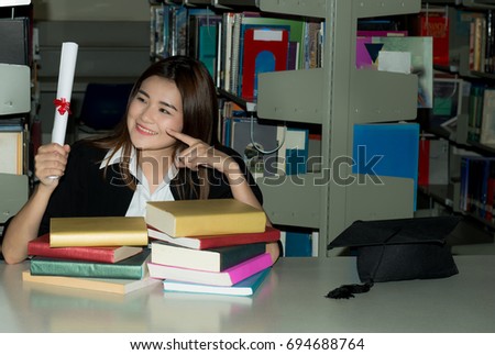 Beautiful Asian female graduate in library on graduation day, Happy female law school graduate in university library ,Age 20-30 years.